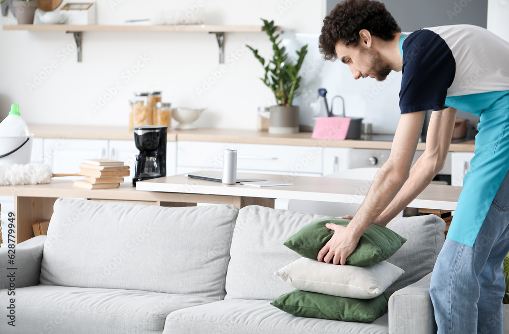 Young man fixing cushion at home