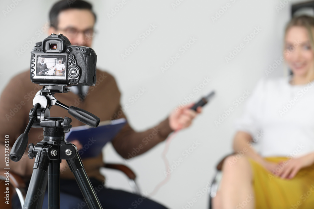 Male journalist with microphone having an interview with woman on camera screen in studio, closeup