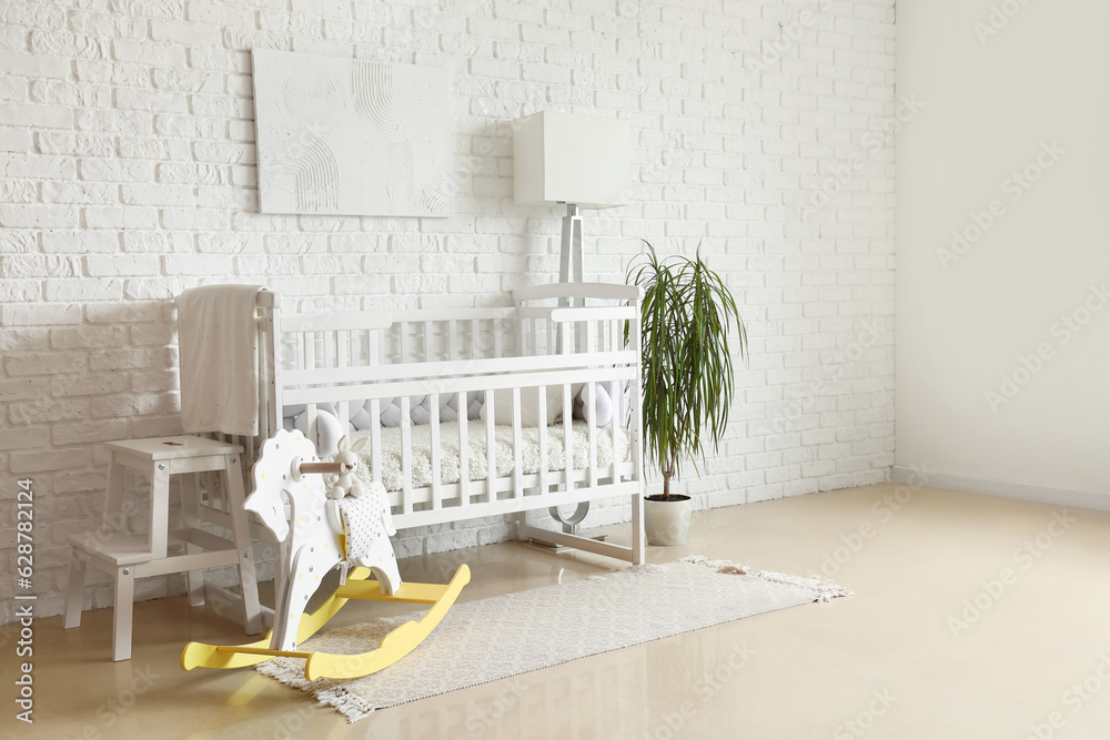 Interior of light bedroom with baby crib, toys and lamp