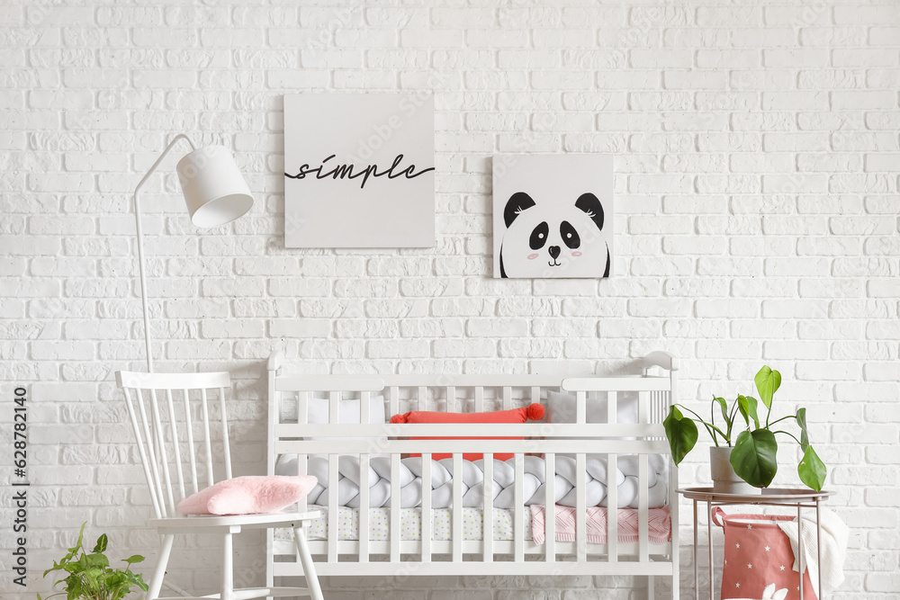 Interior of light bedroom with baby crib and chair