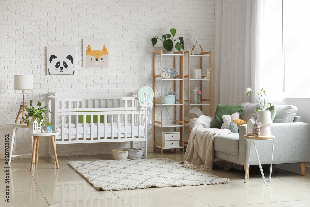 Interior of light bedroom with baby crib, sofa and shelving unit