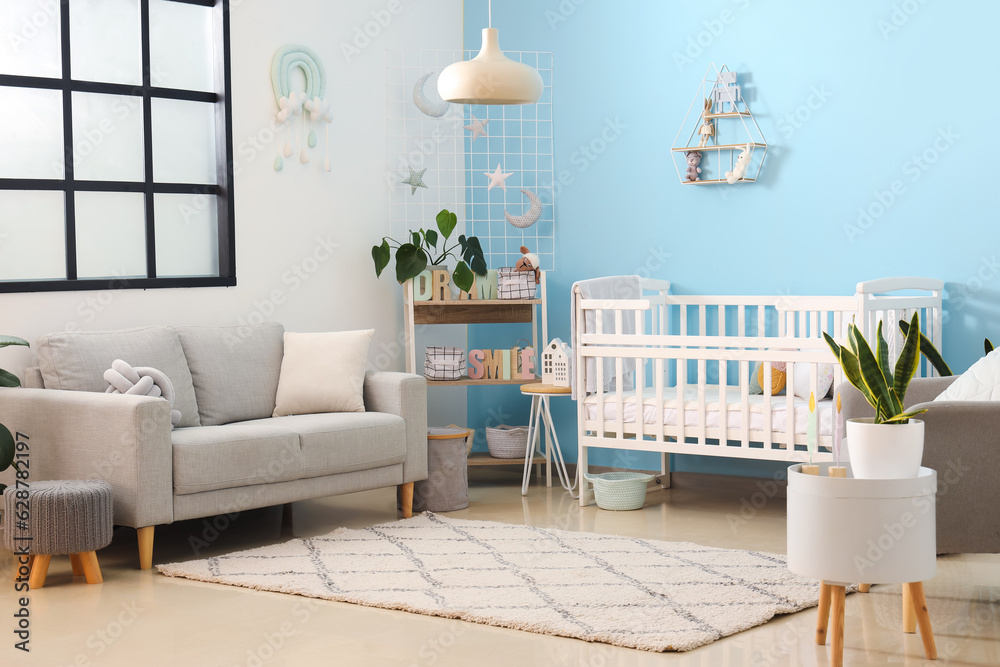 Interior of stylish bedroom with baby crib, sofa and shelving unit