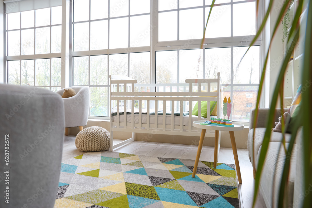 Stylish interior of childrens room with baby bed and big windows