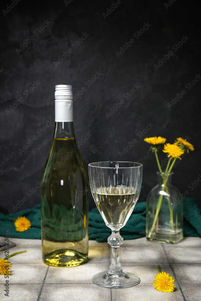 Bottle and glass of dandelion wine on grey tile table