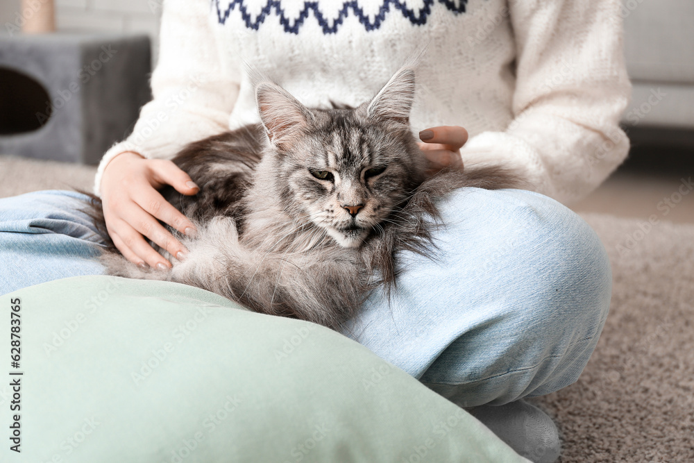 Woman with Maine Coon cat sitting on floor at home