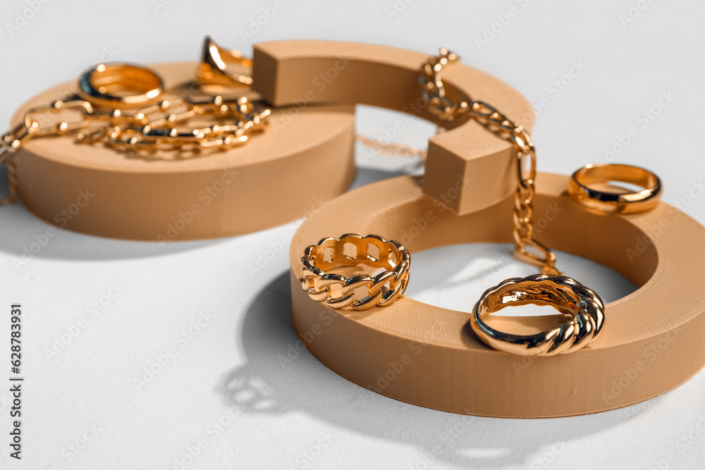 Decorative podiums with golden rings and bracelets on white background