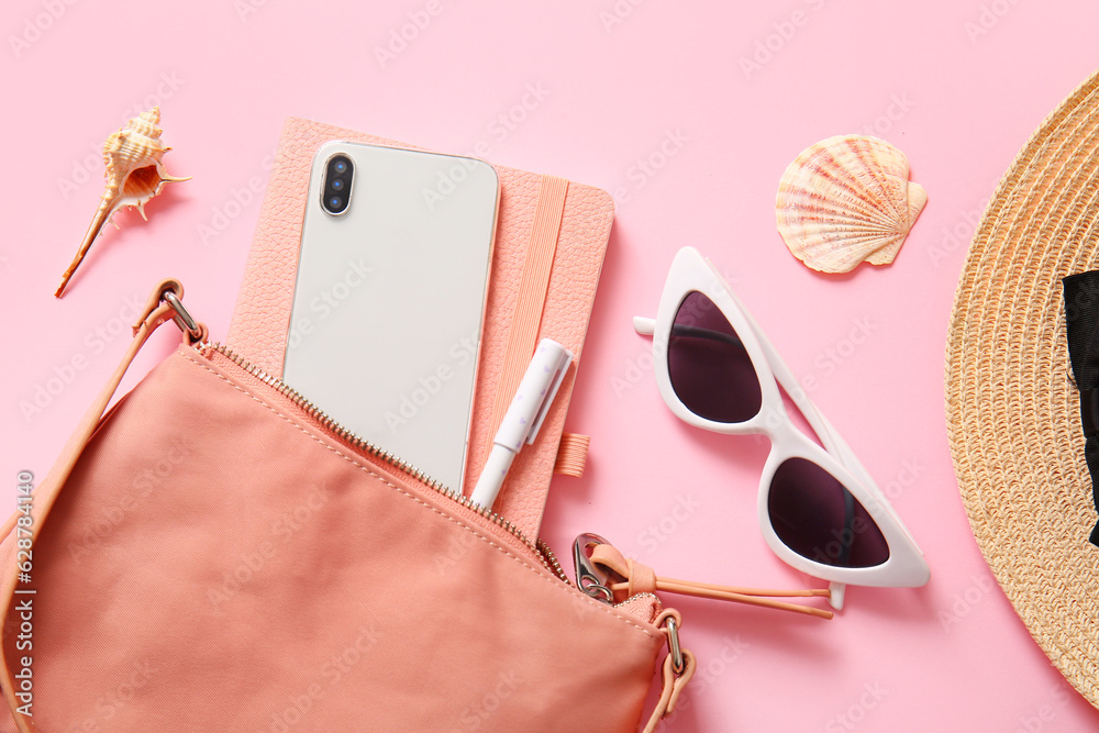 Stylish bag with mobile phone and different accessories on pink background