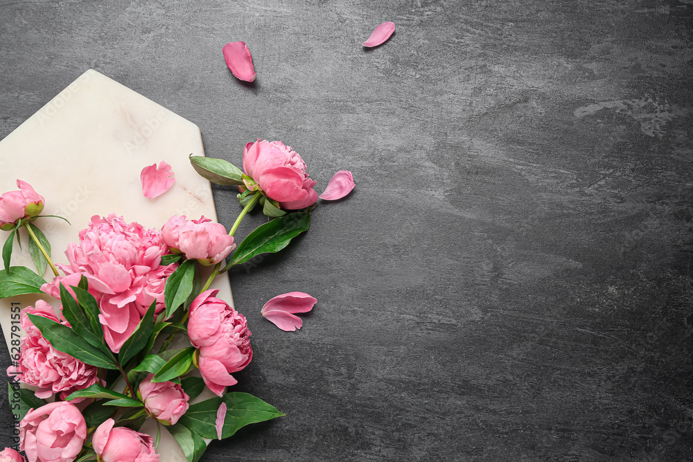 Composition with board and beautiful peony flowers on dark background