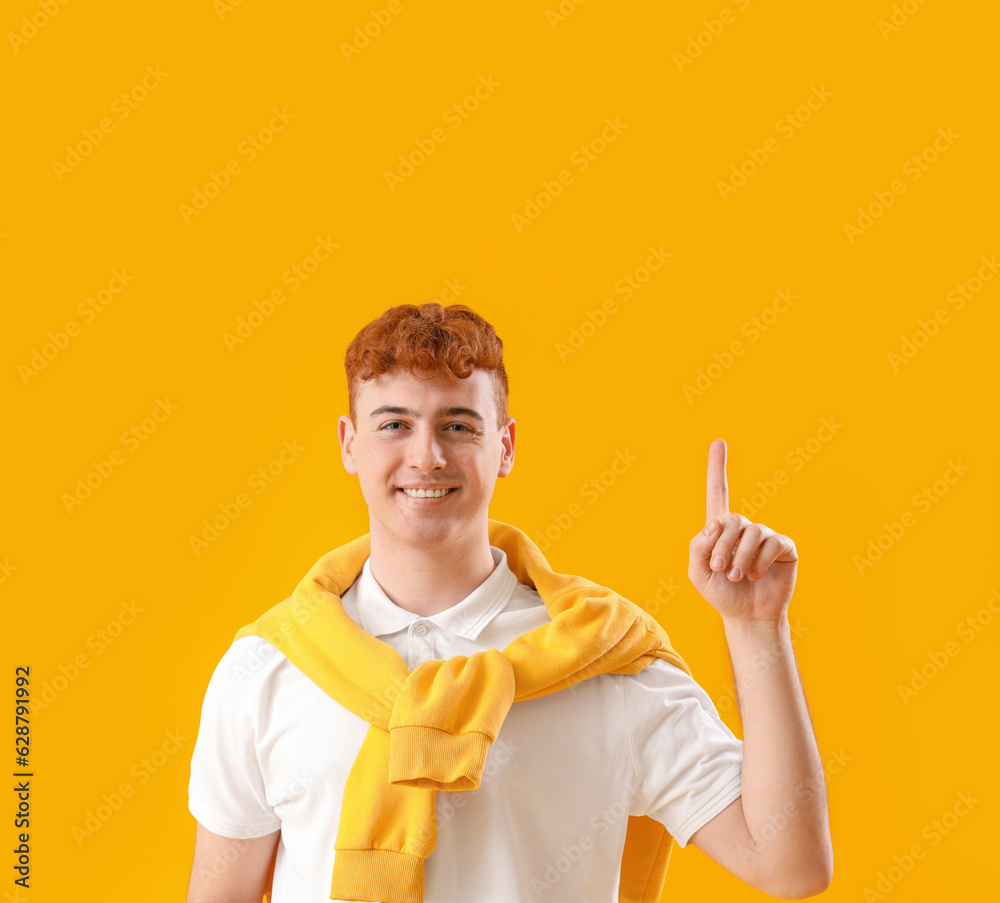 Young redhead man on yellow background