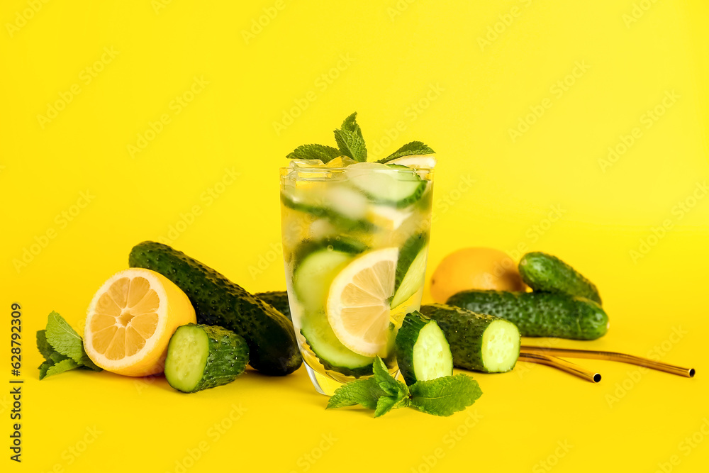 Glass of lemonade with cucumber and mint on yellow background