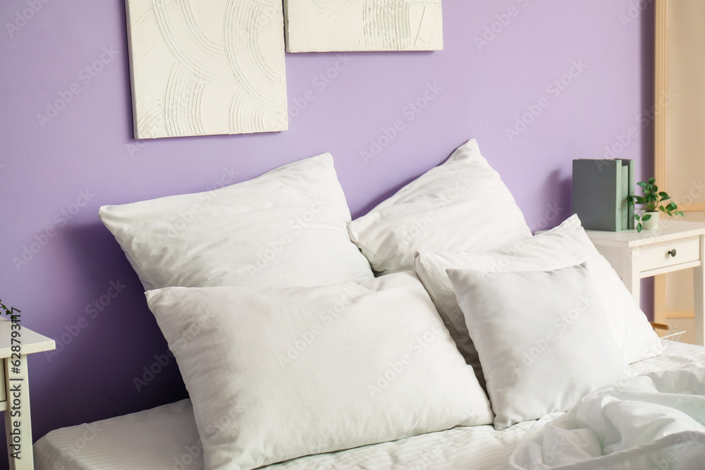 Interior of stylish bedroom with comfortable bed, white pillows and bedside table