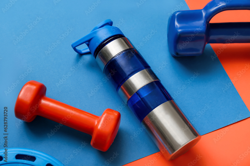 Bottle of water and dumbbells on color background, closeup