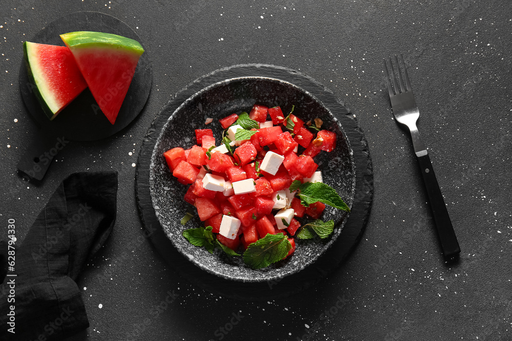 Bowl of tasty watermelon salad on black background