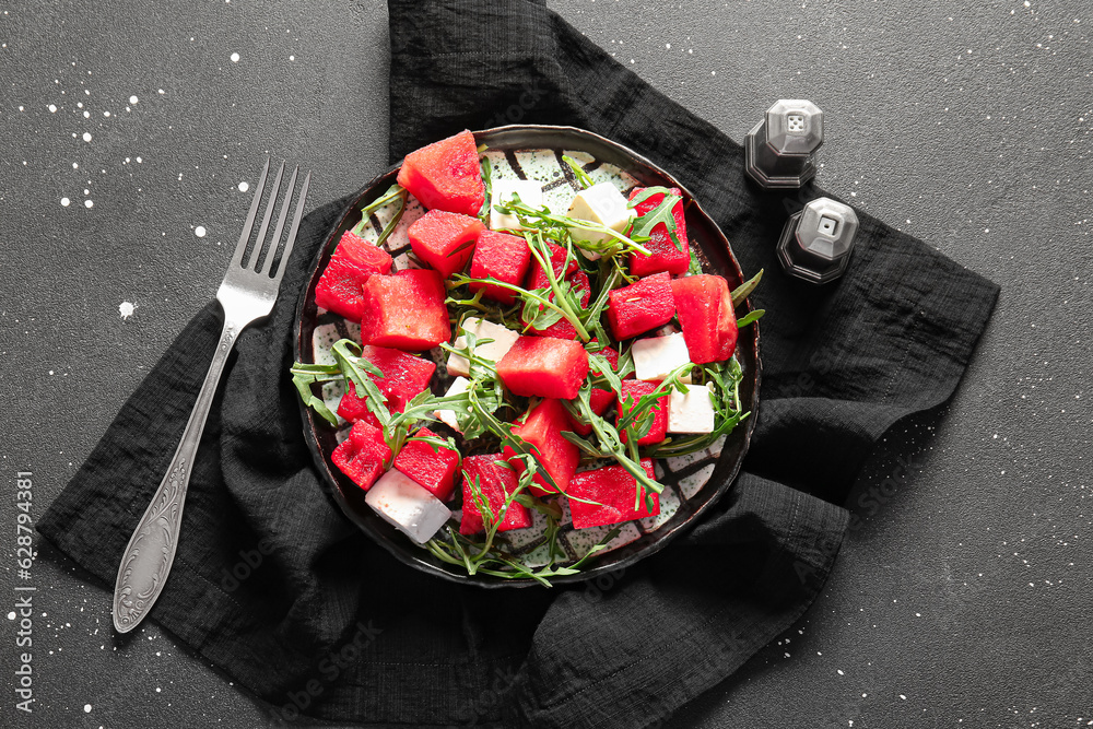 Plate of tasty watermelon salad on black background