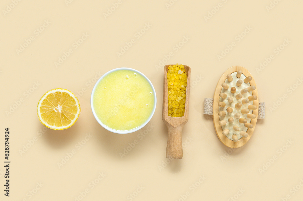 Bowl of lemon body scrub with sea salt and massage brush on beige background