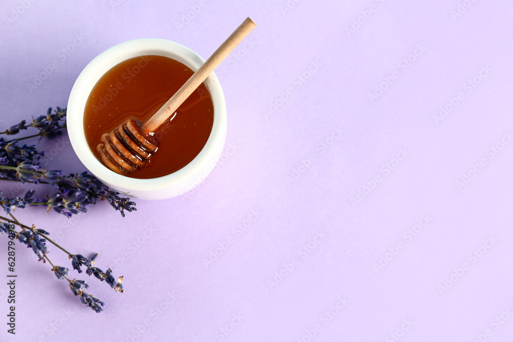 Bowl of sweet lavender honey, dipper and flowers on lilac background