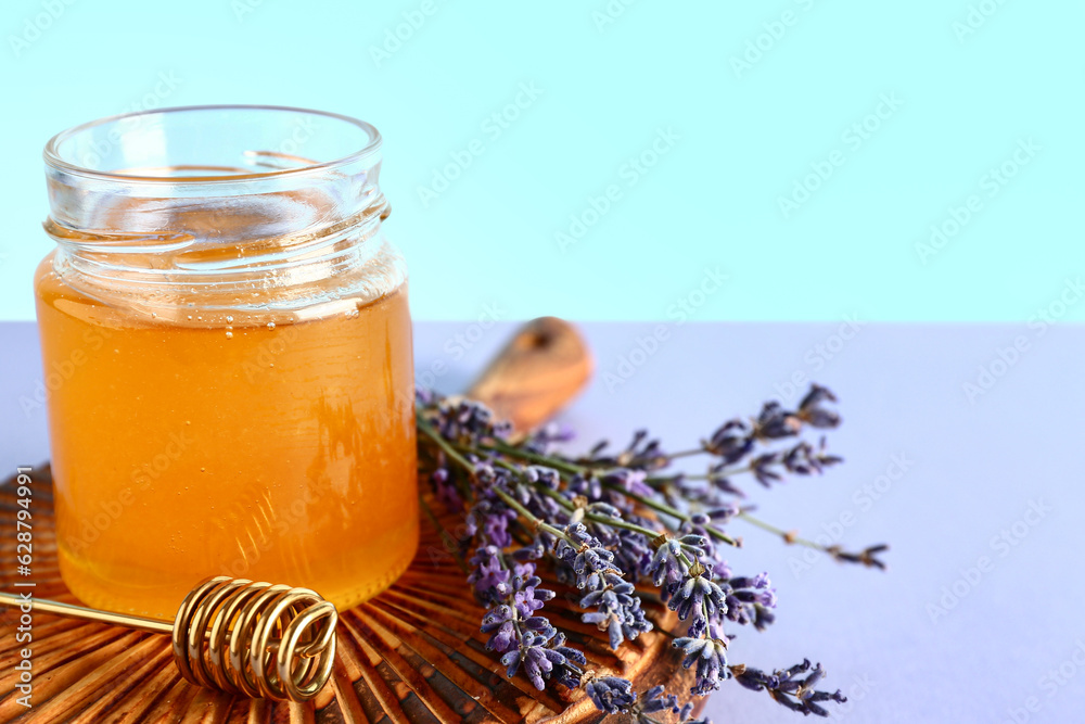 Wooden board with jar of sweet lavender honey, dipper and flowers on lilac table