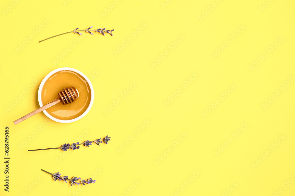 Bowl of sweet lavender honey, dipper and flowers on yellow background