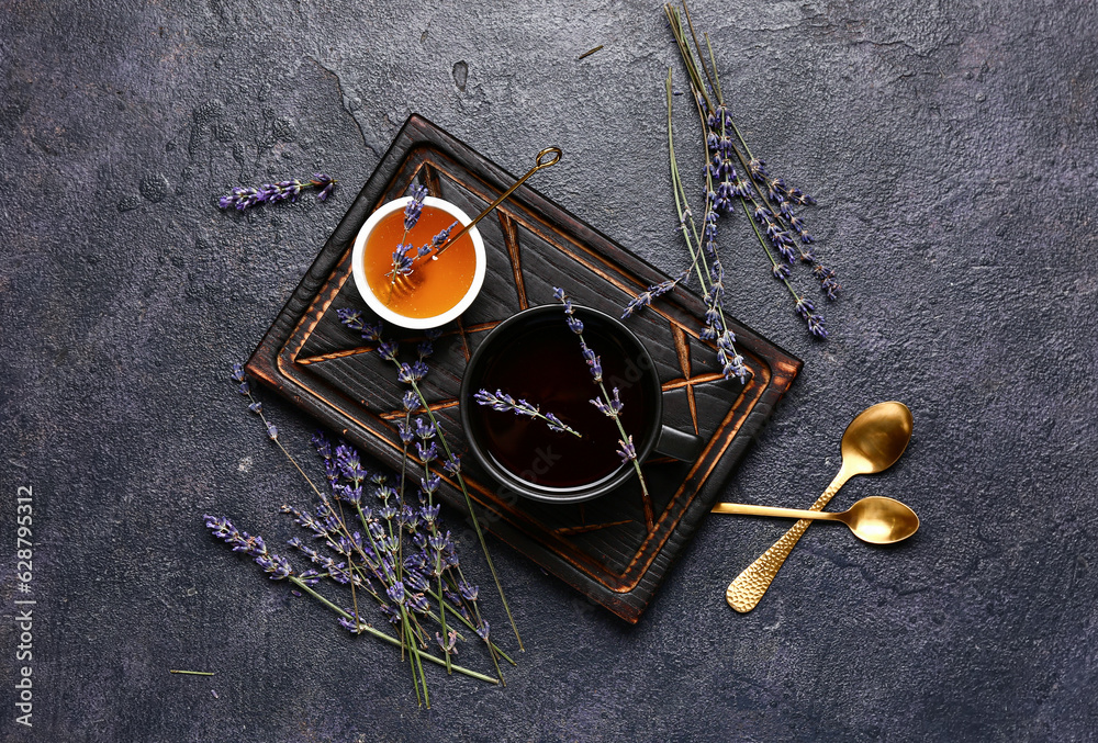 Bowl with sweet lavender honey and cup of tea on dark background