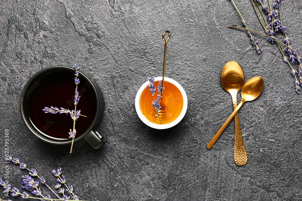 Bowl with sweet lavender honey and cup of tea on dark background