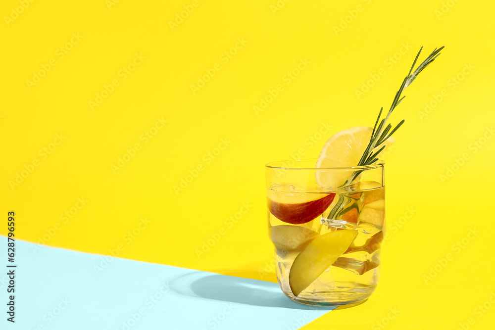 Glass of fresh peach lemonade with rosemary on colorful background