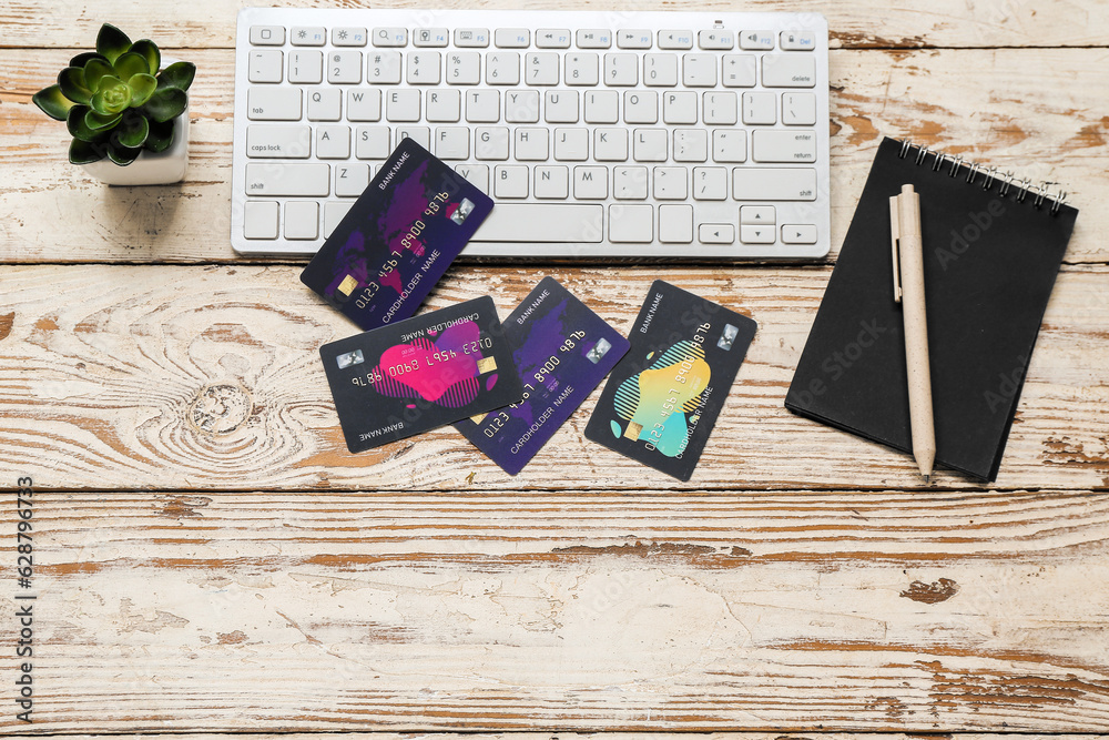 Keyboard with credit cards and notebook on light wooden background