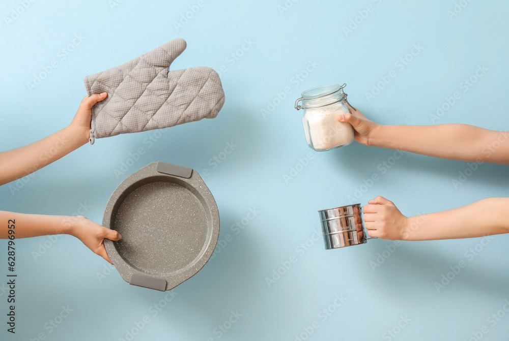 Female hands with baking utensils on blue background