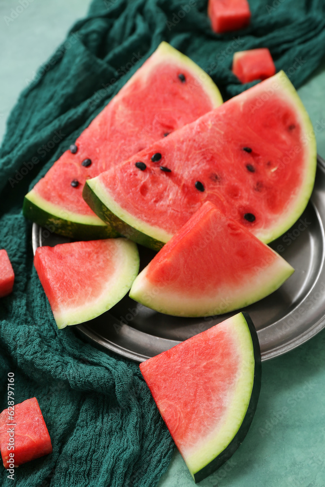 Plate with pieces of fresh watermelon on green background