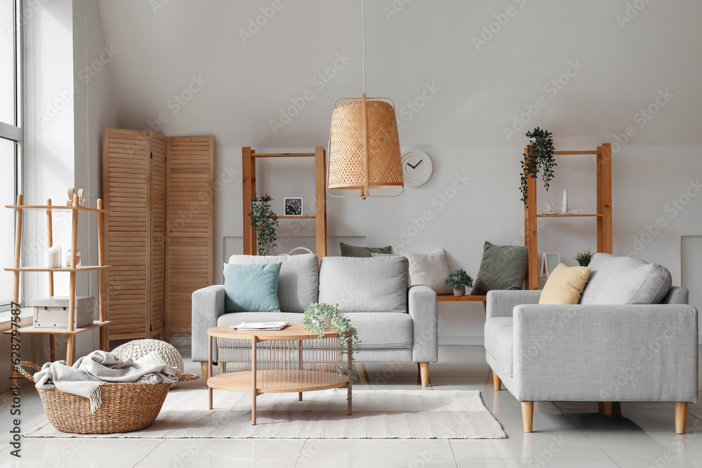 Interior of light living room with cozy grey sofas and wooden coffee table