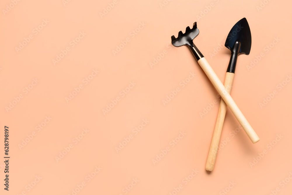 Gardening rake and shovel on beige background