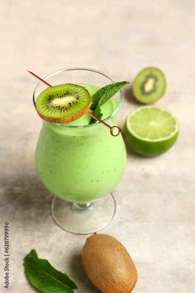 Glass of fresh kiwi smoothie with mint and lime on grey background