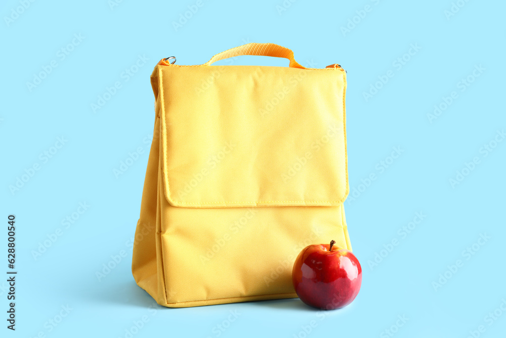 Lunch box bag with fresh apple on blue background