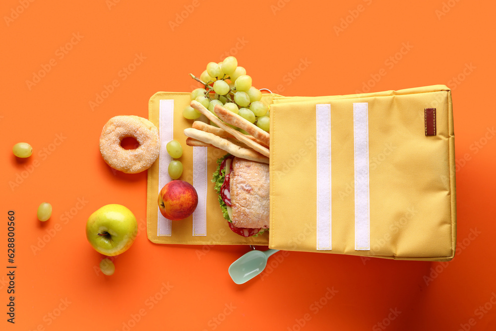 Lunch box bag with different tasty food on orange background