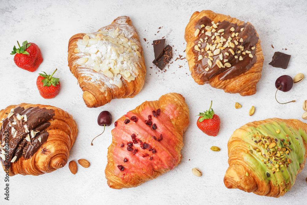 Different sweet croissants and berries on white background