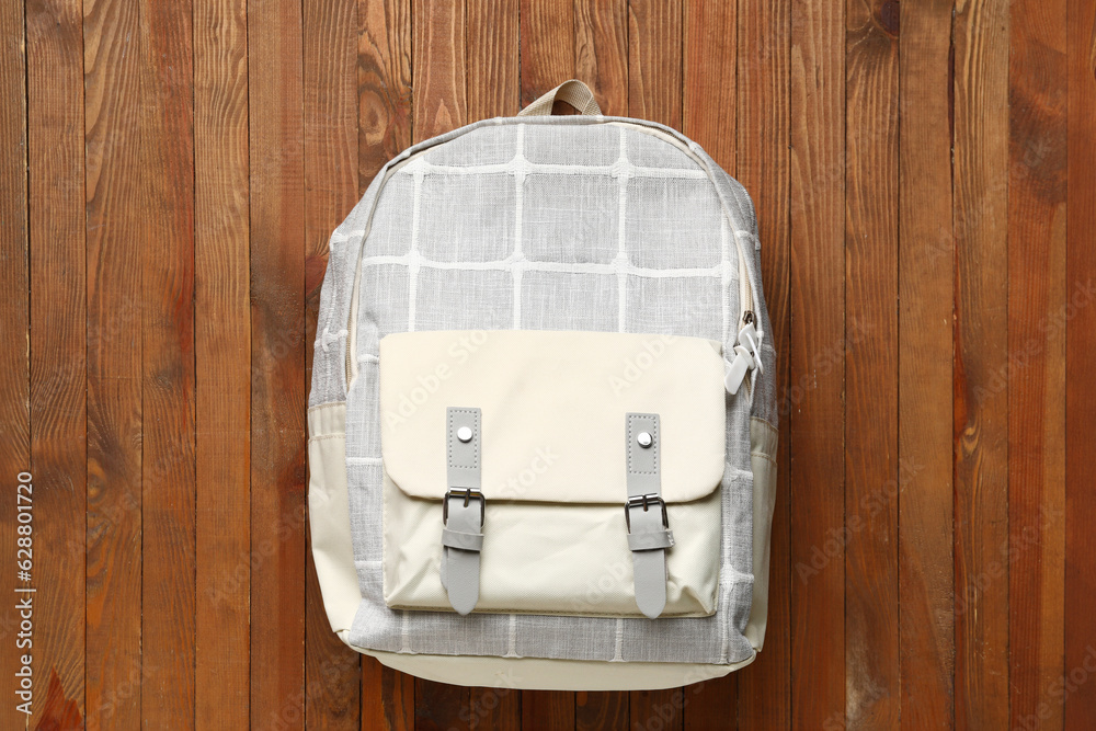 Grey school backpack on wooden background