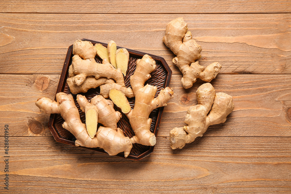 Tray with fresh ginger roots on wooden background