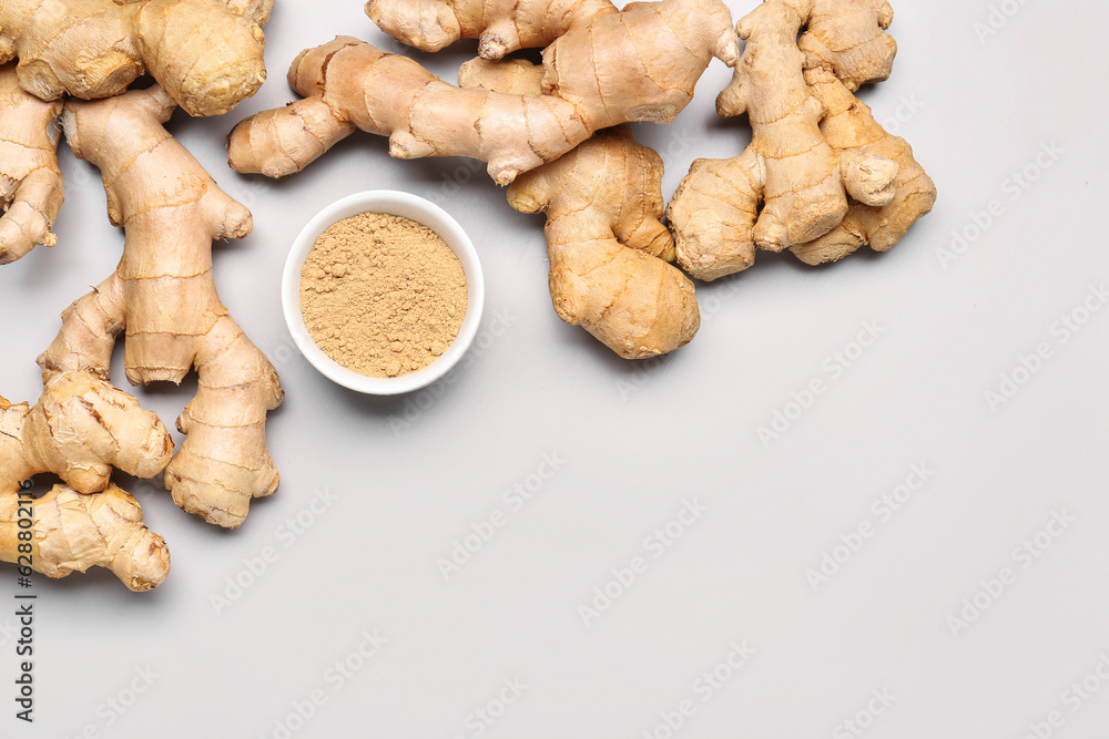 Fresh ginger roots and bowl with dried powder on grey background