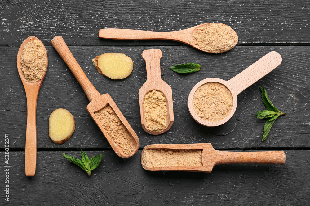 Spoons and scoops with ginger powder on black wooden background