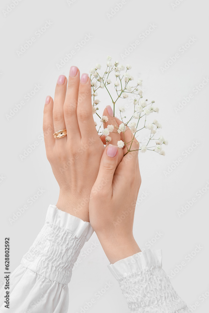 Female hands with beautiful golden ring and gypsophila flowers on white background