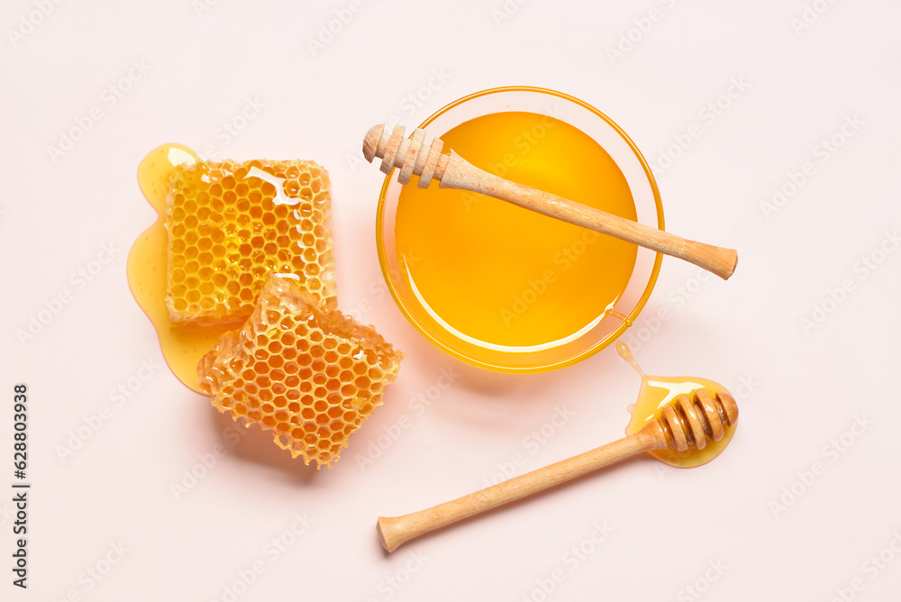 Glass bowl with sweet honey and combs on pink background