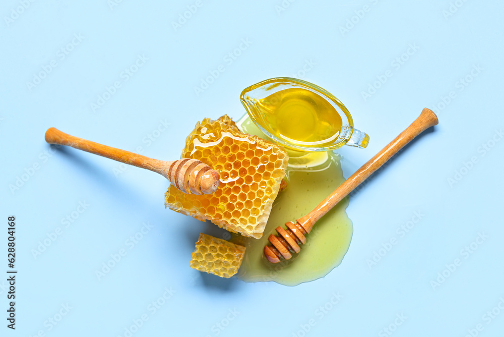 Gravy boat with sweet honey and combs on blue background