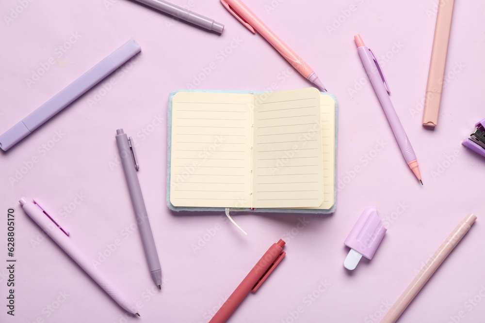 Notebook with different stationery supplies on lilac background