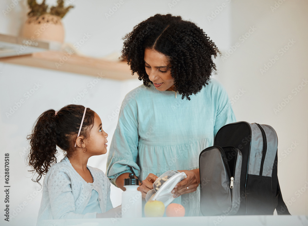 Mother packing lunch for her girl child for health, wellness snacks in the kitchen of their home. Ha