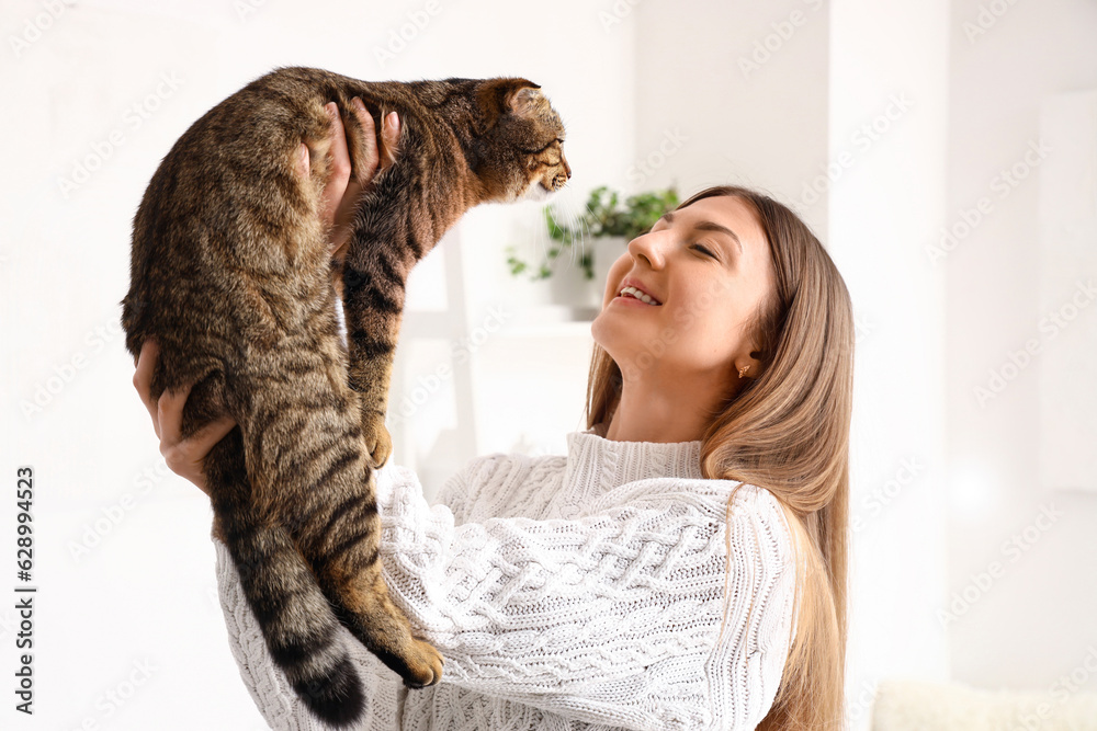 Young woman with striped Scottish fold cat at home