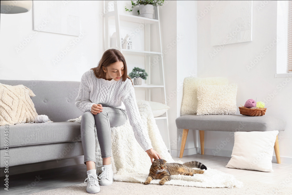 Young woman with striped Scottish fold cat at home