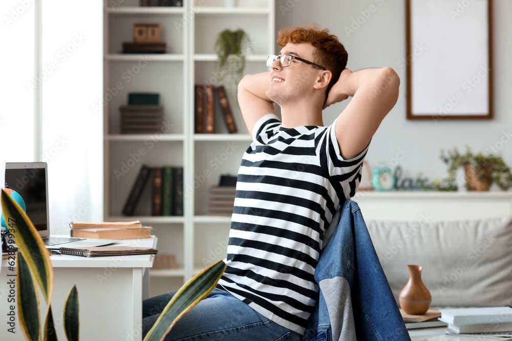 Young redhead man resting in chair at home