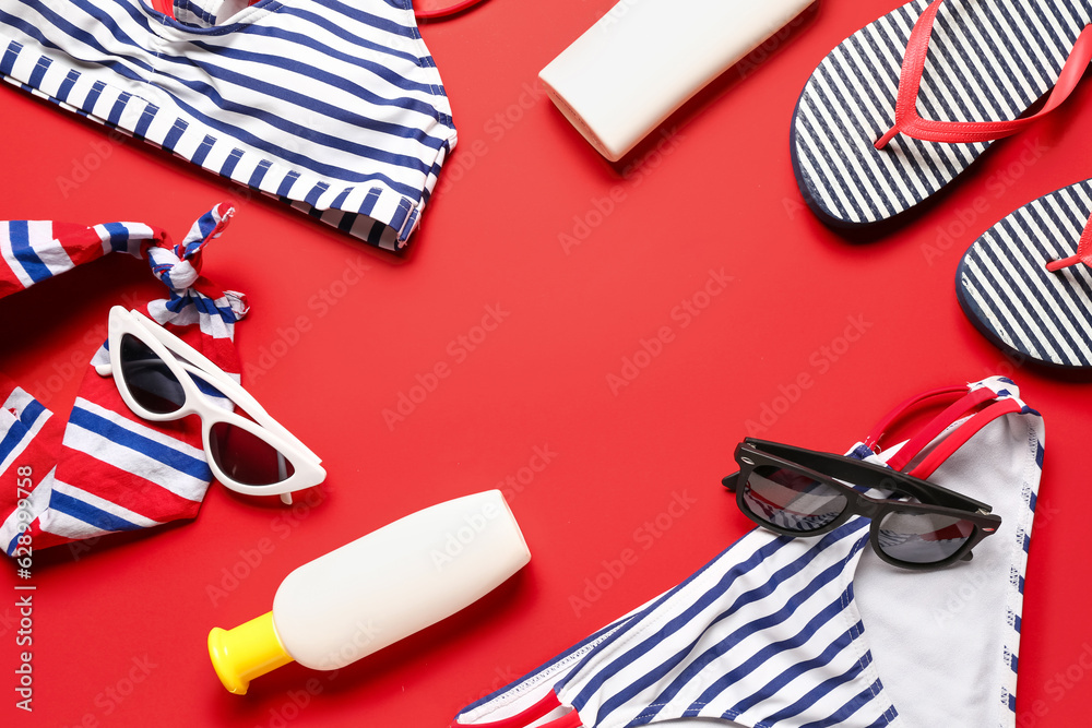 Frame made of sunglasses, swimsuit, flip flops and sunscreen cream on red background