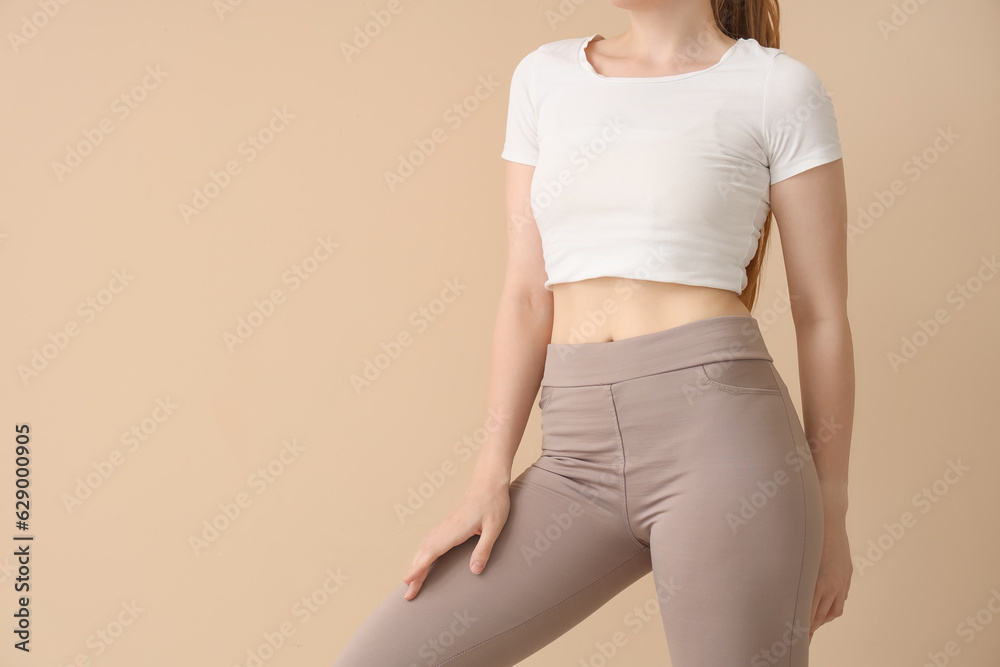 Young woman in sportswear on  beige background