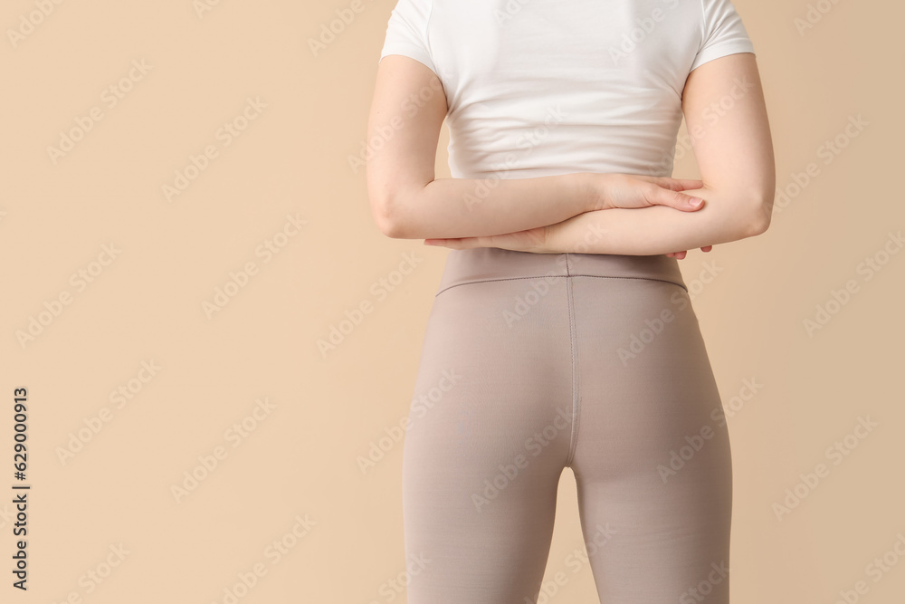 Young woman in sportswear on  beige background, back view