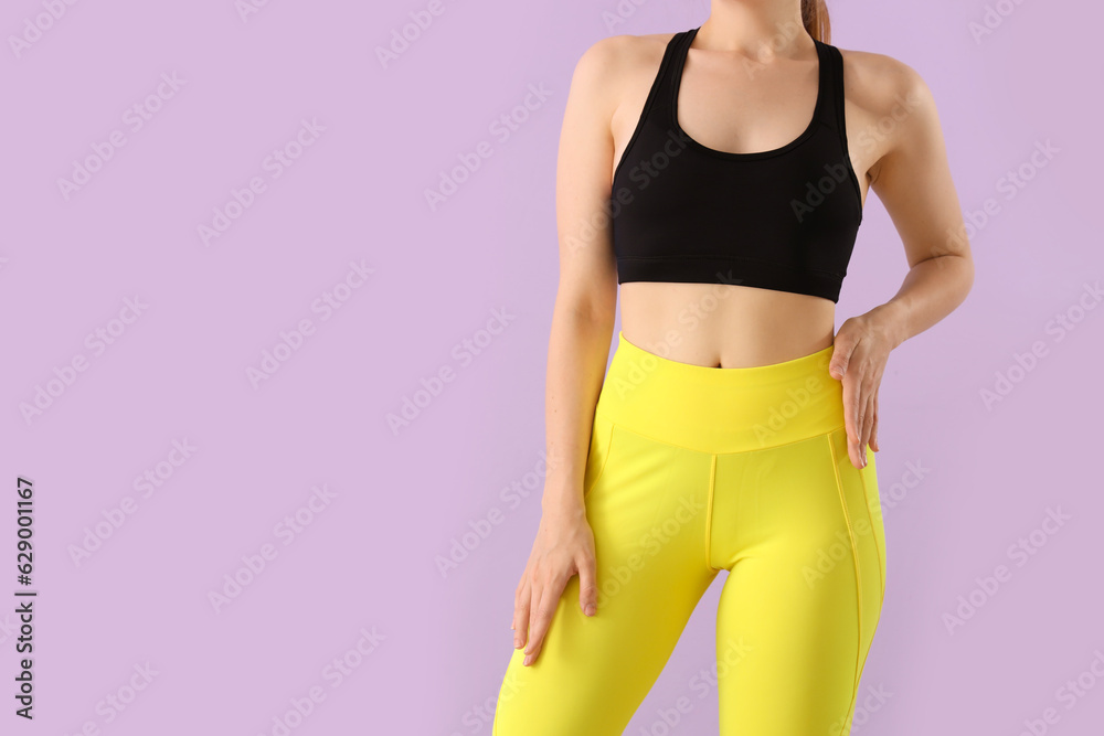 Young woman in sportswear on lilac background